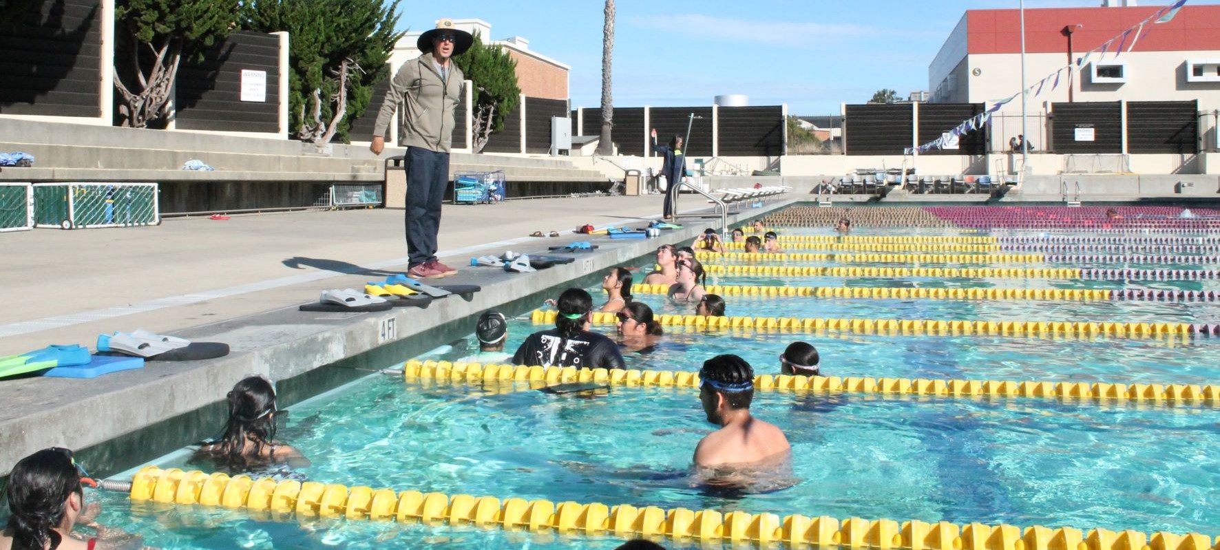 Instructor directs students in swimming pool.