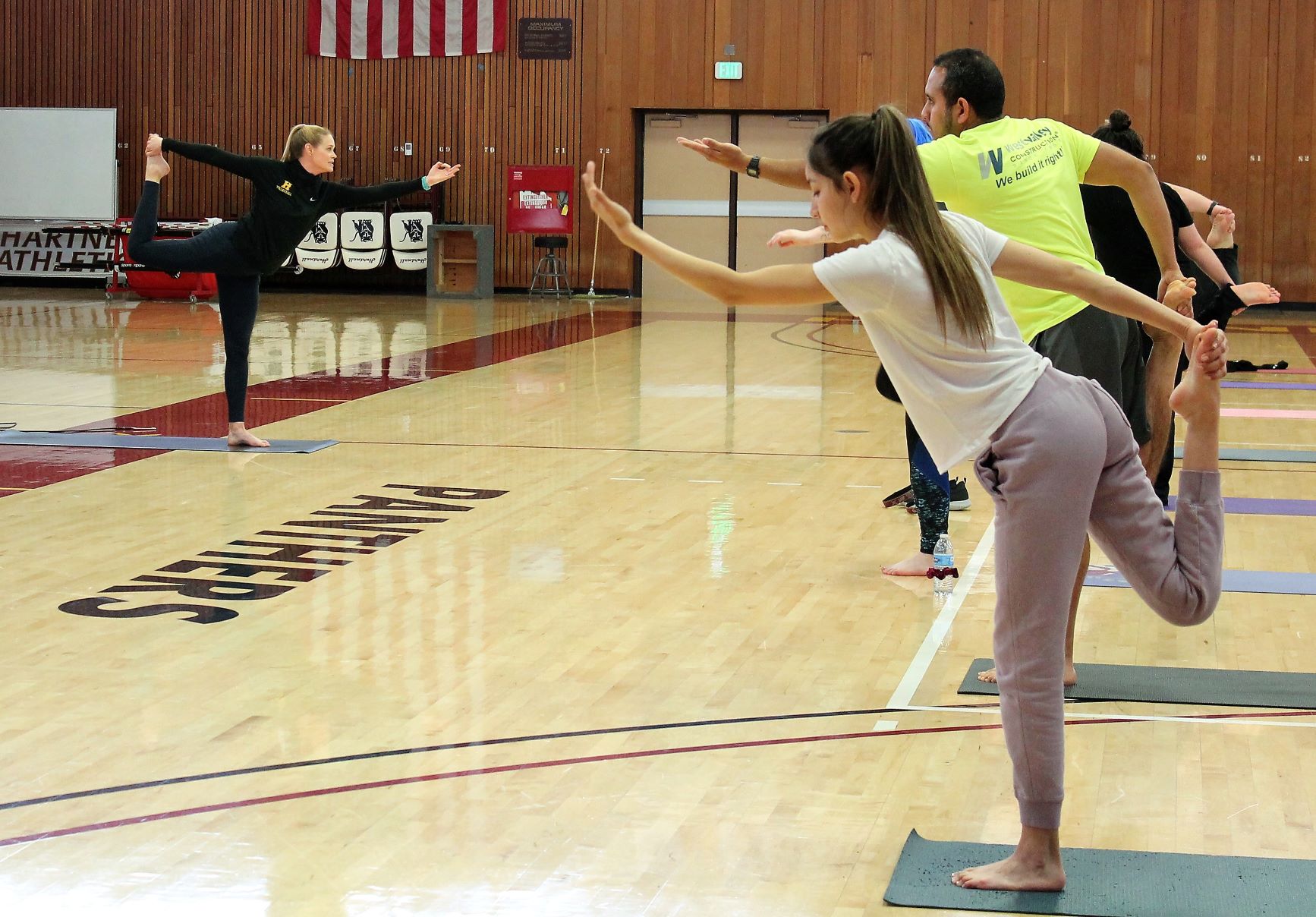 Instructor leads students in yoga class.