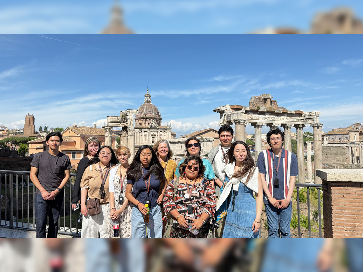 Group of students and travelers pose together overlooking the ancient ruins of the Roman Forum in Rome on a sunny day.