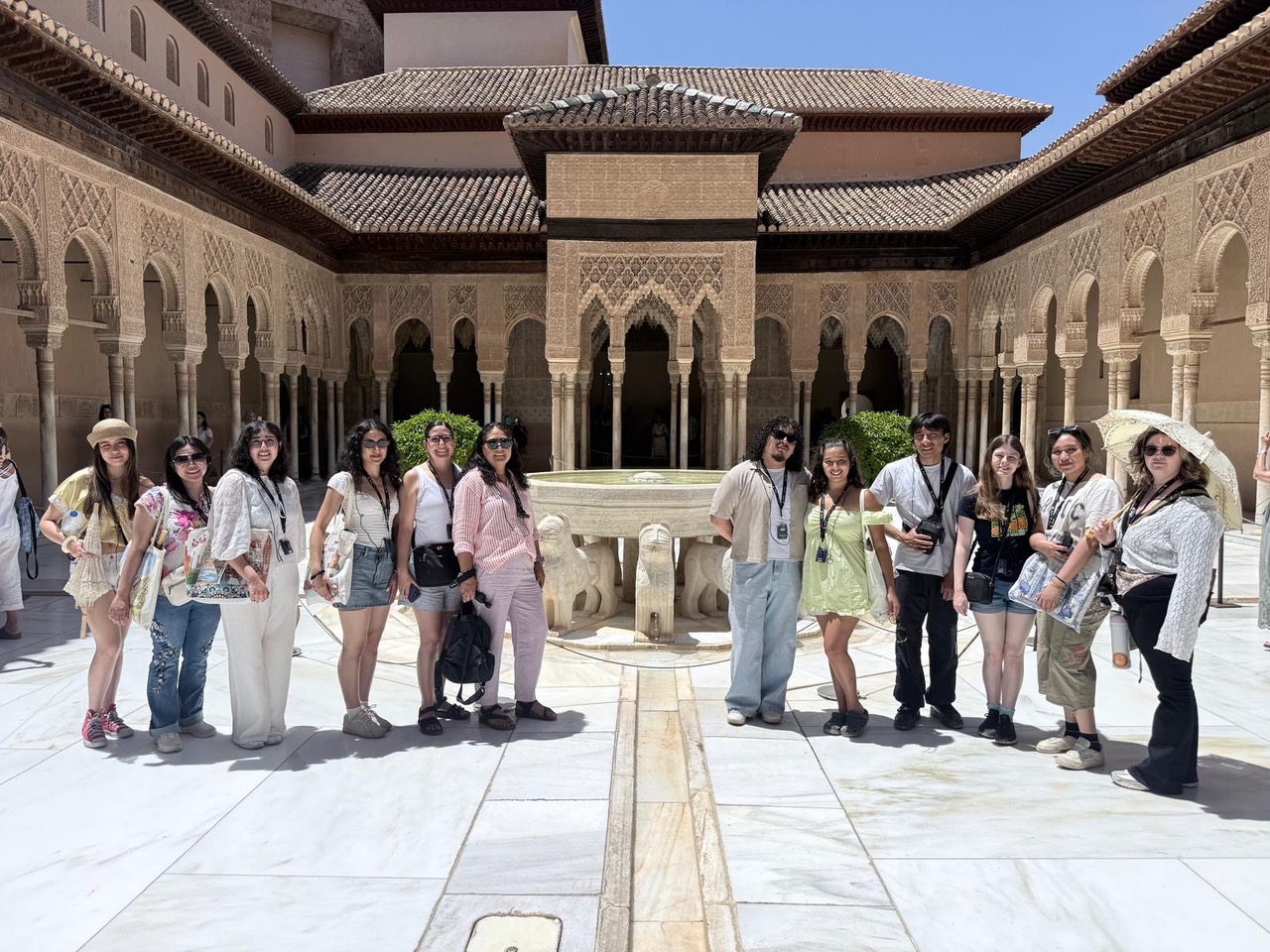 Group of students and travelers pose around a fountain in an ornate courtyard at the Alhambra in Granada, Spain.