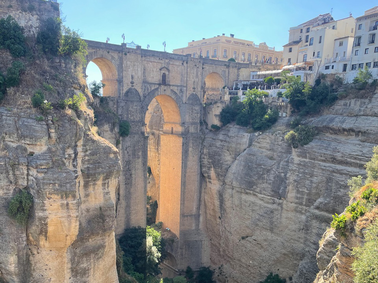 Puente Nuevo stone bridge spans the deep El Tajo gorge in Ronda, Spain, with buildings perched along the cliffs.