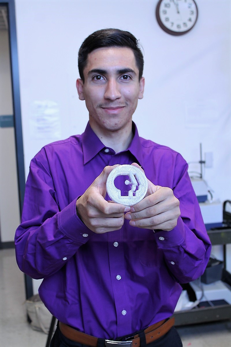 NPS intern Jesus Delgadillo Ponce shows a PBS logo he made using a 3-D printer.