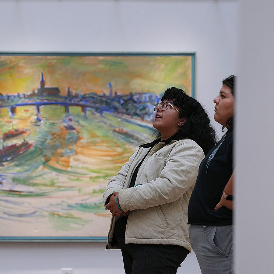students admiring art during art gallery grand opening. There is a large print behind two subjects.