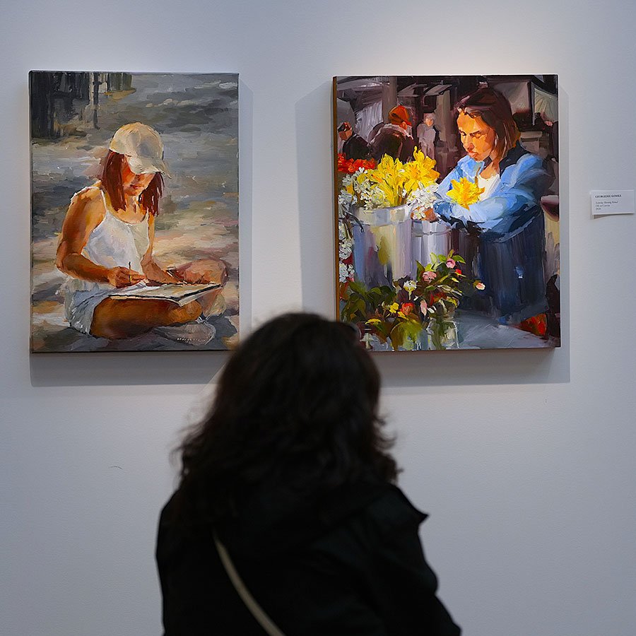 Visitor admiring art insalled on a white wall.