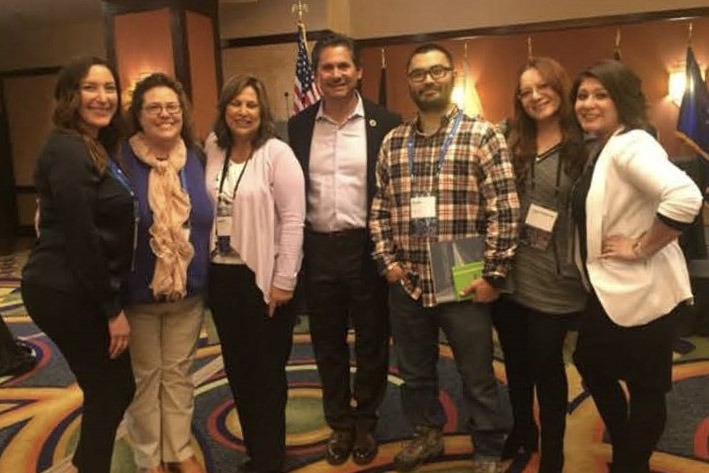Group of professionals standing indoors at a conference, smiling for a group photo.